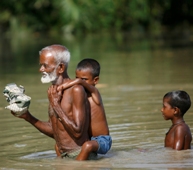 A man makes his way through the flooded village of Godadhar, Bangladesh, with his grandchildren in July 2008. REUTERS/Andrew Biraj