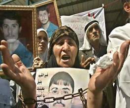 An elderly Jordanian woman holds pictures of Jordanian and Palestinian prisoners, jailed in Israeli prisons, during a protest in front of the United Nations office in Amman, August 23, 2004. Hundreds of Jordanians took part in a sit-in to show solidarity with their relatives and fellow Palestinians who have gone on a hunger strike demanding Israel stop strip searches, allow more frequent family visits, improve sanitary conditions and install public telephones. (Ali Jarekji/Reuters)