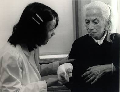Image of a nurse or doctor helping an elderly women with a cast on her hand