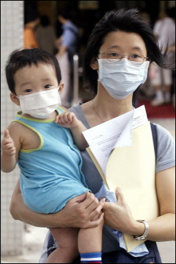 A mother carries her son at the Princess Margaret Hospital, Hong Kong. Another HK hospital has raised a new SARS alert after nine residents of a home for the elderly were treated for fever and respiratory tract infection, a health department spokesman said.(AFP/File/Laurent Fievet)