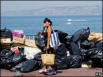 A resident holds her nose as she walks past piles of rubbish bags and boxes left on the Kennedy corniche in Marseille, southern France, 8 June 2003