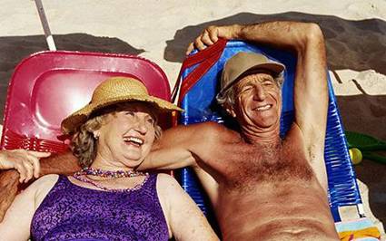 Man and woman enjoying the sunshine on the beach: Sunbathing 'could boost your intellect and prevent dementia'