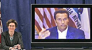 Appearing via video conference California Gov. Arnold Schwarzenegger discusses his plan to extend health coverage to nearly all Californians during a news conference in Sacramento, Calif. on Monday, Jan. 8, 2007, as Kim Belshe, Secretary for the Department of Health and Human Services looks on at left.