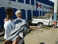A Haitian family escapes flood waters 
that have surrounded their home and home 
business, a garage, near Gonaives, Haiti,
 on September 20, 2004. Haitians were 
caught off guard by flooding resulting 
from Tropical Storm Jeanne. REUTERS/
Daniel 
Morel