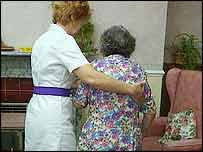An elderly lady is helped to her chair