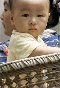 A baby is carried in a basket on his mother's back on a street in Beijing.