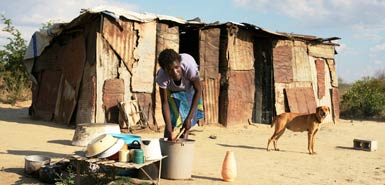 A young Zimbabwean woman washes her pots outside her shack outside Bulawayo in Zimbabwe